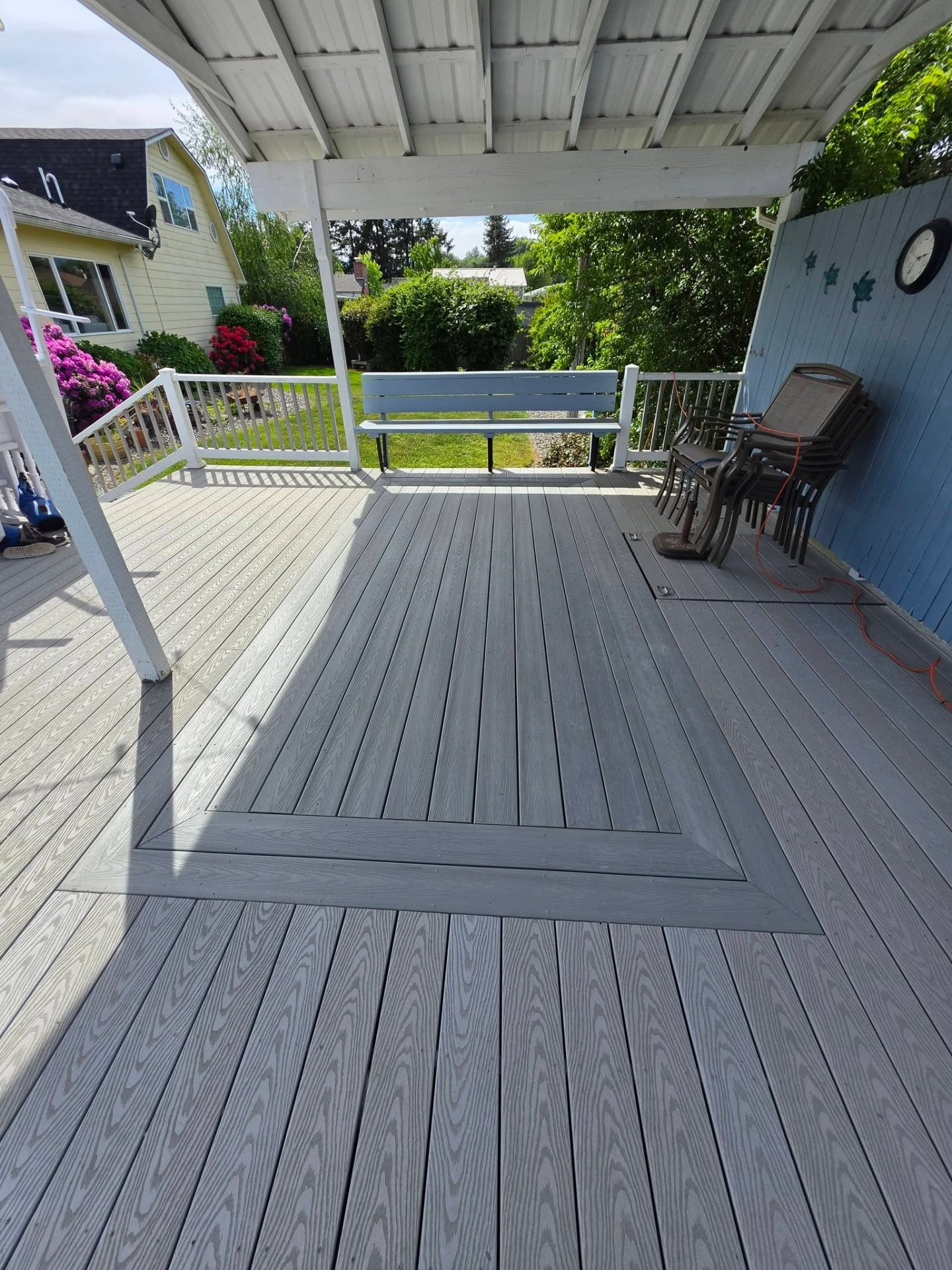 Covered backyard porch with two-tone gray composite decking and bordered inlay