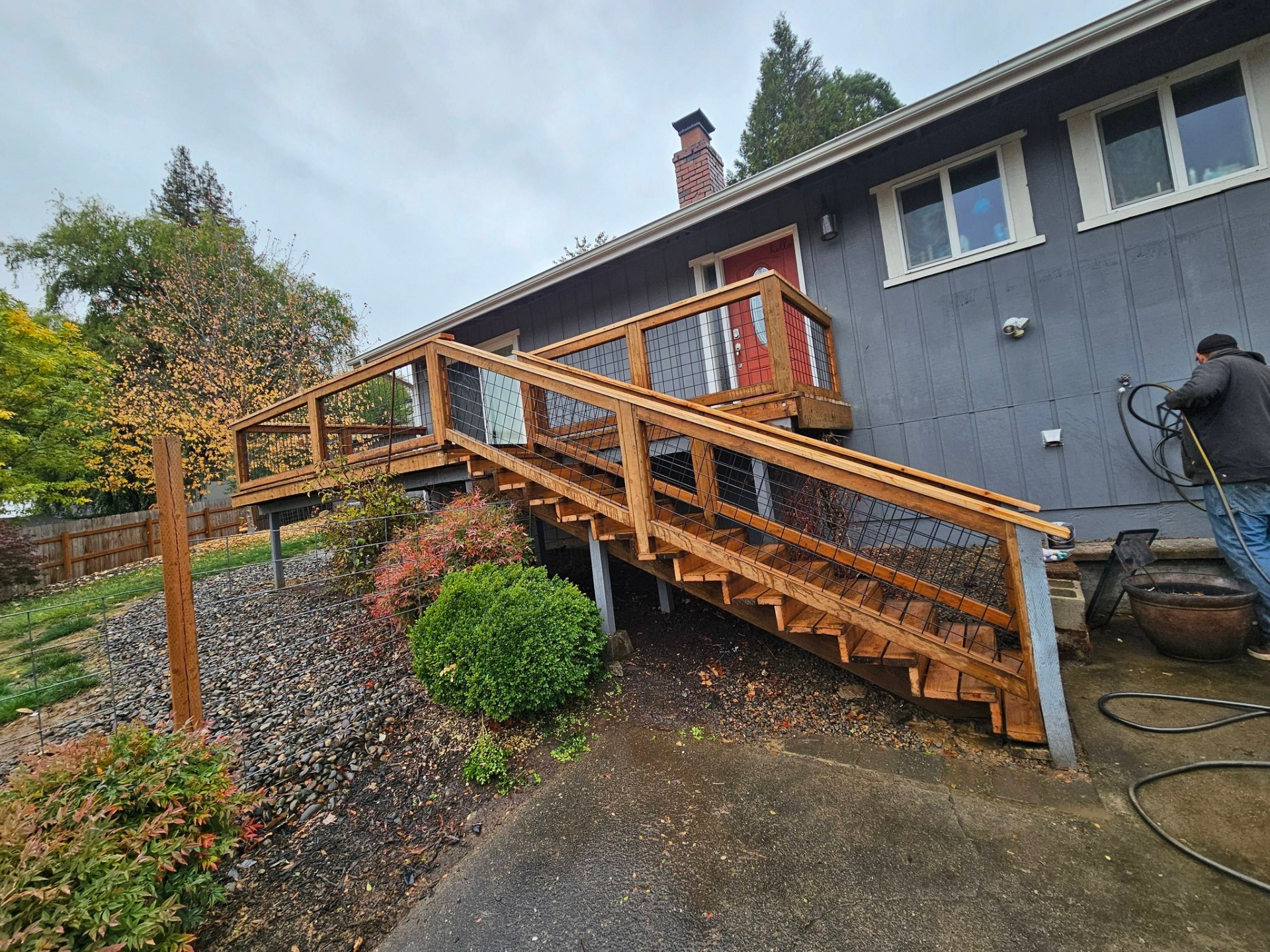 Long cedar staircase with hog-wire railings leading up to a hillside home entry