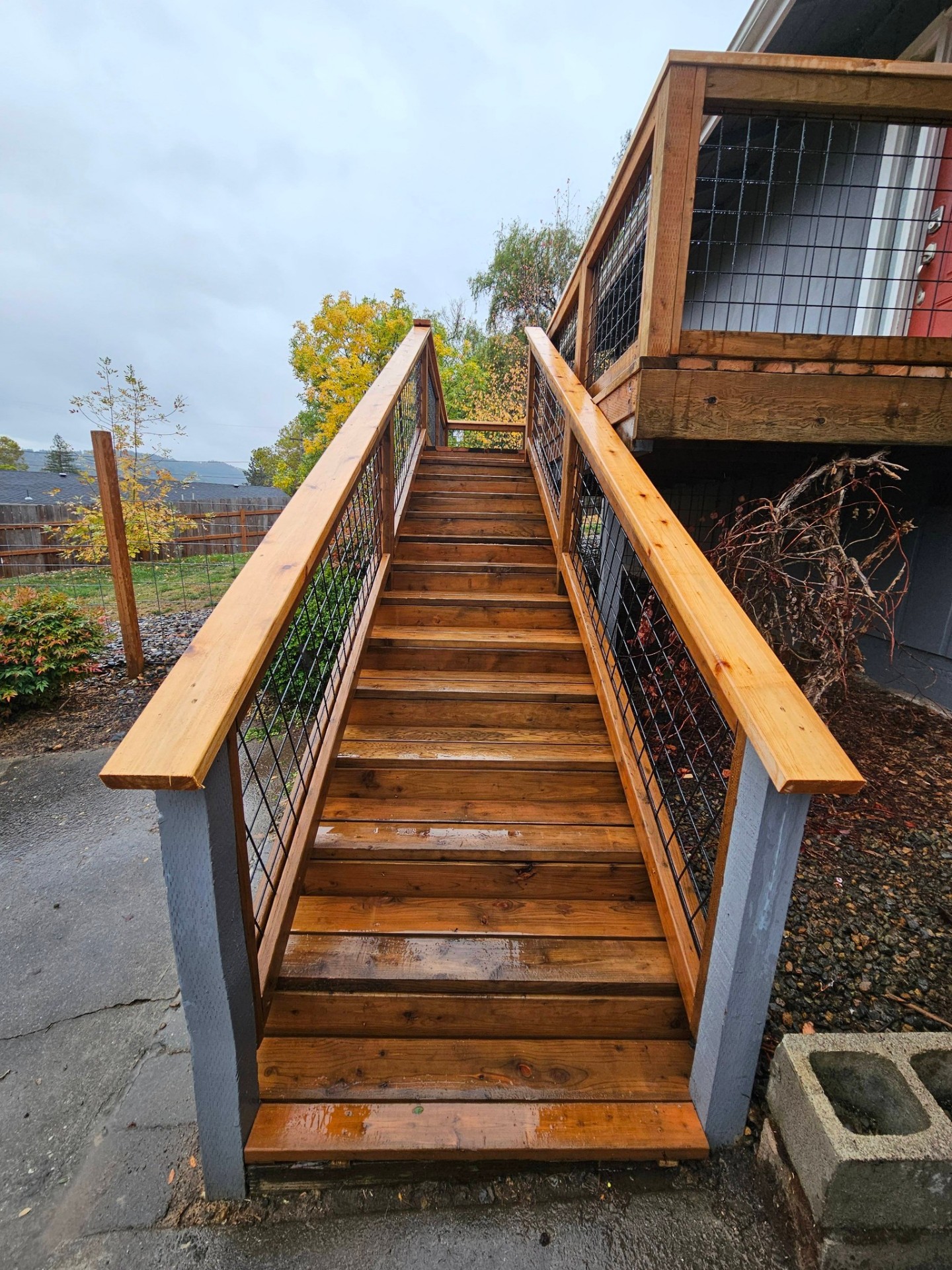 Wide cedar staircase with hog-wire railings leading up to a back deck
