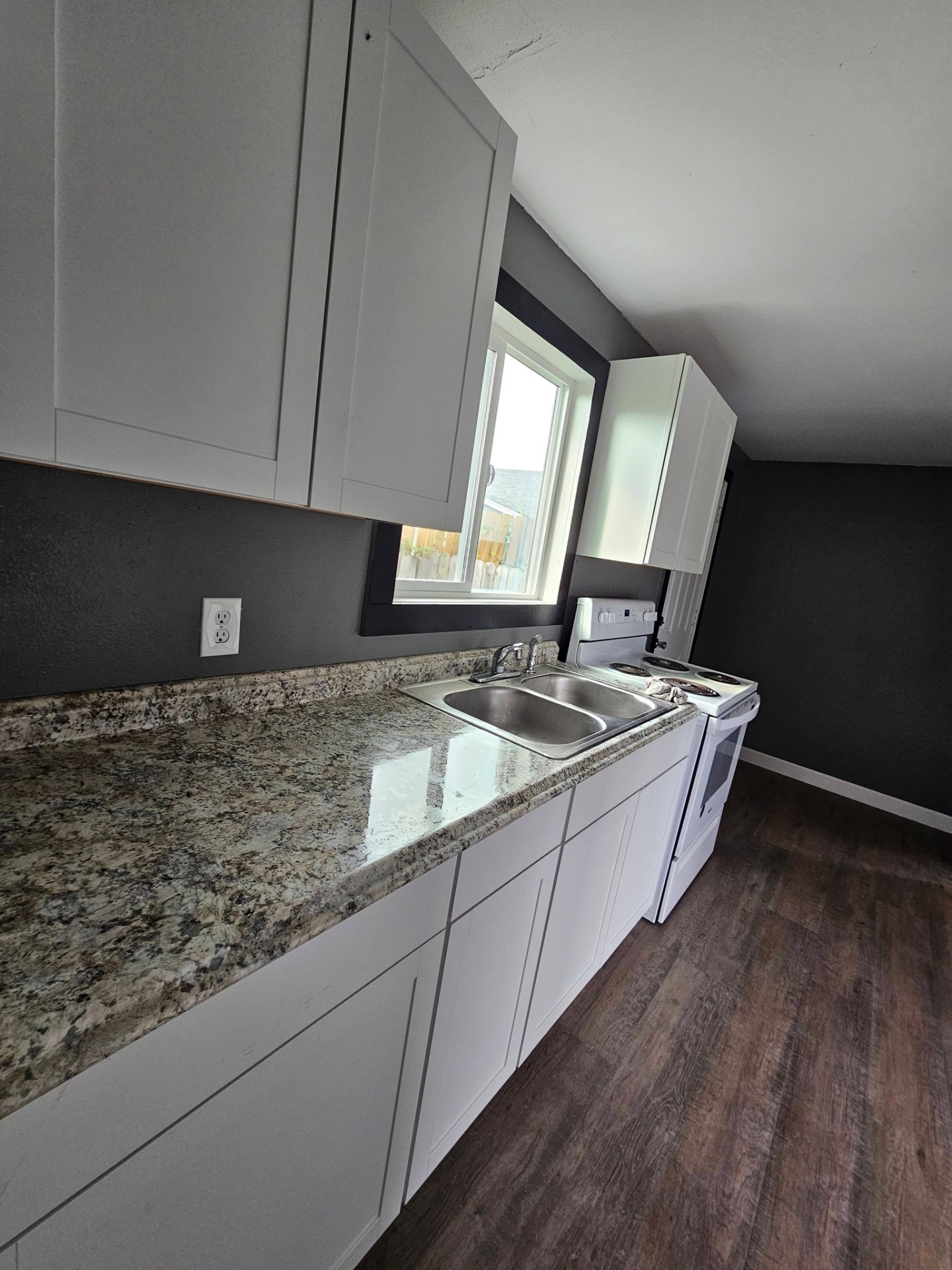 Renovated galley kitchen with white shaker cabinets and granite counters